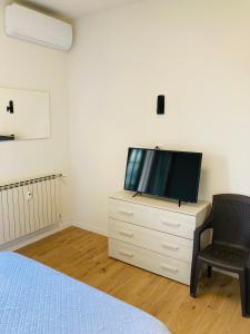 a bedroom with a television on a dresser with a chair at Guido's Apartment Villa Romana in Desenzano del Garda