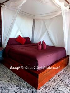 a bedroom with a bed with red pillows at Sabai Sabai Beach Bungalows in Ko Phayam