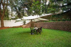 a table and chairs under an umbrella in a yard at La Bougainvillea with BBQ Grill at Porvorim by StayVista in Sinquerim