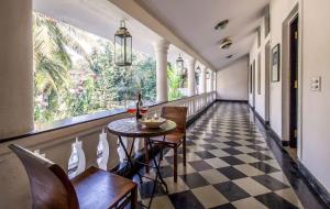 a hallway with a table and chairs and a window at La Bougainvillea with BBQ Grill at Porvorim by StayVista in Sinquerim