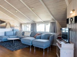 ein Wohnzimmer mit blauen Sofas und einem Fernseher in der Unterkunft Bright Dune View Cottage-By Traum in Bjerregård