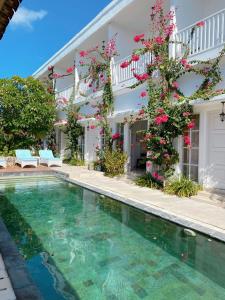 a villa with a swimming pool in front of a house at Hikari Guesthouse in Seminyak
