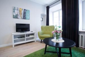 un soggiorno con sedia verde e tavolo di Baron Old Town Apartments a Vilnius