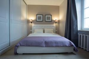 a bedroom with a white bed and two pictures on the wall at Baron Old Town Apartments in Vilnius