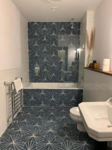 y baño con ducha de azulejos azules y blancos. en Royal Bolthole, en Edimburgo