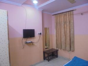 a room with a tv on the wall and a table at Hotel Raj Guest House in Jaipur