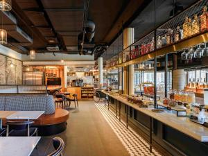 a restaurant with a bar with tables and chairs at ibis Landshut City in Landshut