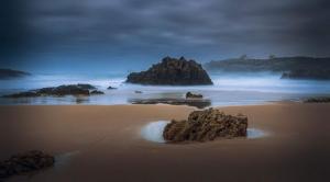 a beach with rocks in the sand and the ocean at Posada La Morena in Soto de la Marina