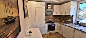 uma cozinha com armários brancos e um lavatório em Nida Kopu 3 Apartment em Nida