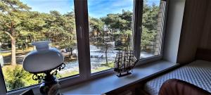 a lamp sitting on a window sill with a view of a river at Nida Kopu 3 Apartment in Nida