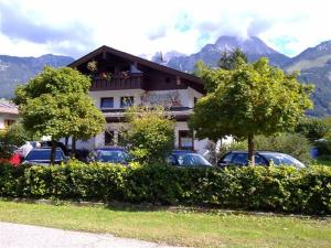 une maison avec des voitures garées devant elle et des montagnes dans l'établissement Alpenpension Bergidyll, à Schönau am Königssee