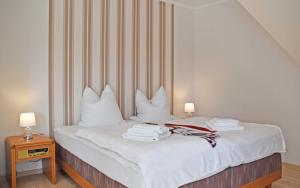 Schlafzimmer mit einem Bett mit weißer Bettwäsche und Kissen in der Unterkunft Ferienwohnung Wiesenblick in Kerkwitz