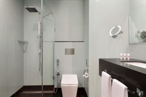 a bathroom with a shower and a toilet and a sink at Ramada Encore by Wyndham Muscat Al-Ghubra in Muscat
