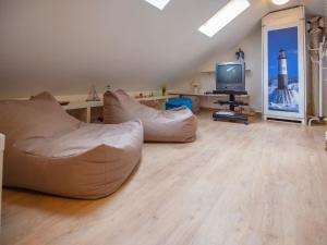 ein Wohnzimmer mit einem weißen Sofa und einem TV in der Unterkunft Dünenpark Binz - Komfort Ferienwohnung mit 1 Schlafzimmer und Balkon im Dachgeschoss 023 in Binz