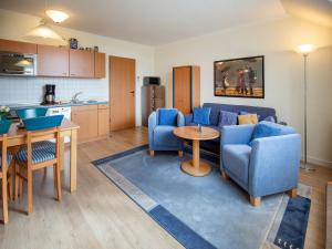 ein Wohnzimmer mit einem blauen Sofa und einem Tisch in der Unterkunft Dünenpark Binz - Komfort Ferienwohnung mit 1 Schlafzimmer und Balkon im Dachgeschoss 023 in Binz