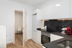 a kitchen with white cabinets and black counter tops at Hauzify I Apartament Big Family in Sant Feliu de Guixols +15 photos
