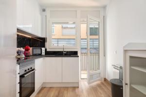 a kitchen with white cabinets and a window at Hauzify I Apartament Big Family in Sant Feliu de Guíxols