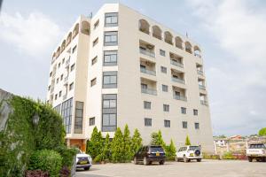 利伯维尔Hotel Hibiscus Louis的一座白色的大建筑,汽车停在停车场
