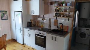 a kitchen with white cabinets and a sink and a refrigerator at Podlaskie Żuczki in Żuki