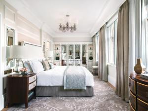 a bedroom with a bed and a desk and windows at The Langham London in London
