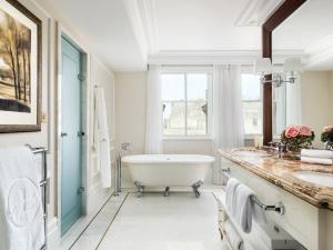 a bathroom with a tub and two sinks and a window at The Langham London in London