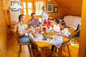 una familia cenando en una mesa en una cabaña en Farm Stay Pirc, en Laško
