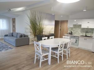 cocina y sala de estar con mesa blanca y sillas en Chopina 29 Sopot Apartments, en Sopot