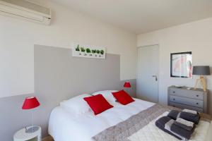 een witte slaapkamer met een groot wit bed met rode kussens bij Cosy and large flat in the hypercentre of Avignon Provence - Welkeys in Avignon