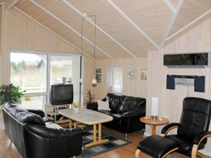 sala de estar con muebles de cuero negro y TV en Holiday Home Raade III en Årøsund