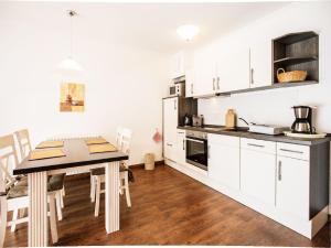 eine Küche mit weißen Schränken und einem Tisch und Stühlen in der Unterkunft Dünenpark Binz - Komfortplus Ferienwohnung mit 1 Schlafzimmer und Terrasse im Erdgeschoss 099 in Binz