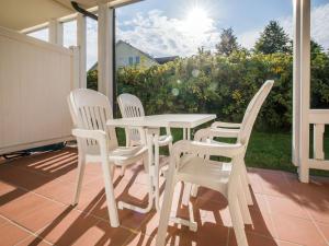 einen weißen Tisch und 4 Stühle auf einer Terrasse in der Unterkunft Dünenpark Binz - Komfortplus Ferienwohnung mit 1 Schlafzimmer und Terrasse im Erdgeschoss 099 in Binz