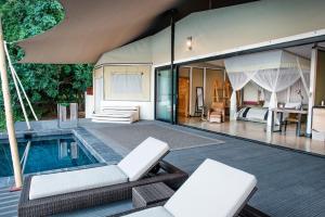 a villa with a swimming pool and a bedroom at Sausage Tree Camp 
