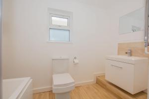 a white bathroom with a toilet and a sink at By Lushlets - City Centre Hot tub Pool table - Great for Hens Stags & Rugby groups! in Cardiff +80 photos