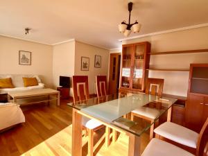 Housingleón - San Marcos con garaje في ليون: غرفة معيشة مع طاولة زجاجية وأريكة