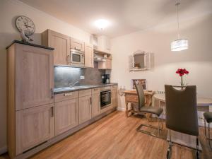 eine Küche mit Holzschränken, einem Tisch und einem Schreibtisch in der Unterkunft Dünenpark Binz - Komfortplus Ferienwohnung mit 1 Schlafzimmer und Terrasse im Erdgeschoss 128 in Binz