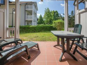 eine Terrasse mit 2 Stühlen, einem Tisch und Bänken in der Unterkunft Dünenpark Binz - Komfortplus Ferienwohnung mit 1 Schlafzimmer und Terrasse im Erdgeschoss 128 in Binz
