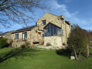 a stone house with large windows and a yard at Oaklodge House in Leyburn