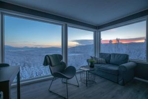 a living room with a couch and chairs in front of windows at Aurora Borealis Observatory in Silsand