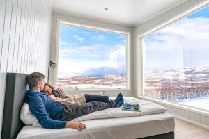 a couple laying on a bed looking out a window at Aurora Borealis Observatory in Silsand
