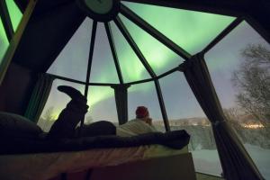 a person sitting in a window looking at the northern lights at Aurora Borealis Observatory in Silsand