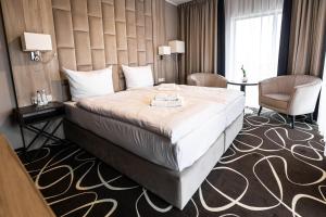 a hotel room with a large bed and a chair at Trofana Wellness & SPA in Międzyzdroje
