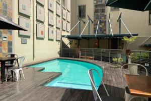 a swimming pool with a table and chairs next to a building at Cool & Easy Flat in the heart of Marshalltown in Johannesburg