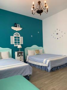 馬公市的住宿－浪漫滿屋渡假別墅民宿，一间卧室设有两张带蓝色墙壁和吊灯的床。