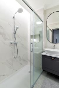 a white bathroom with a shower and a sink at Apartamenty Bazyliańska 1 lok 4 in Zamość