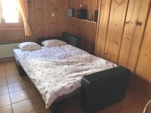 un piccolo letto in una camera con pareti in legno di Chalet Le Biolley 2 a Orsières