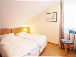 ein Schlafzimmer mit einem großen weißen Bett und einem Stuhl in der Unterkunft Dünenpark Binz - Komfort Ferienwohnung mit 1 Schlafzimmer und Balkon im Dachgeschoss 236 in Binz