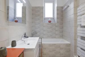 La salle de bains blanche est pourvue d'un lavabo, d'une baignoire et de fenêtres. dans l'établissement Appartement Sereno - Welkeys, à Biarritz 4 autres photos