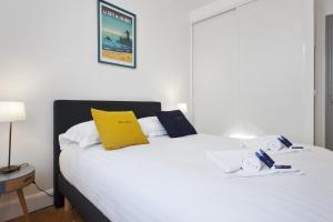 - une chambre avec un lit blanc et un oreiller jaune dans l'établissement Superb and calm T3 in the heart of Biarritz - Welkeys, à Biarritz