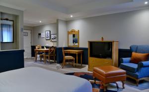 um quarto de hotel com uma cama e uma televisão e cadeiras em Courtyard Hotel Rosebank em Joanesburgo