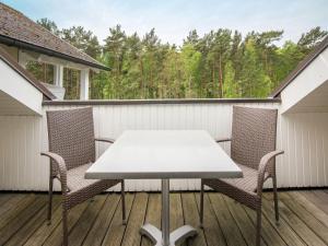 einen Tisch und Stühle auf einer Terrasse mit Blick auf die Bäume in der Unterkunft Dünenpark Binz - Komfort Ferienwohnung mit 1 Schlafzimmer und Balkon im Dachgeschoss 293 in Binz